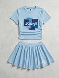 Silent Sky Set: light blue cropped ribbed top with patchwork cross and Basenji script, paired with a pleated mini skirt