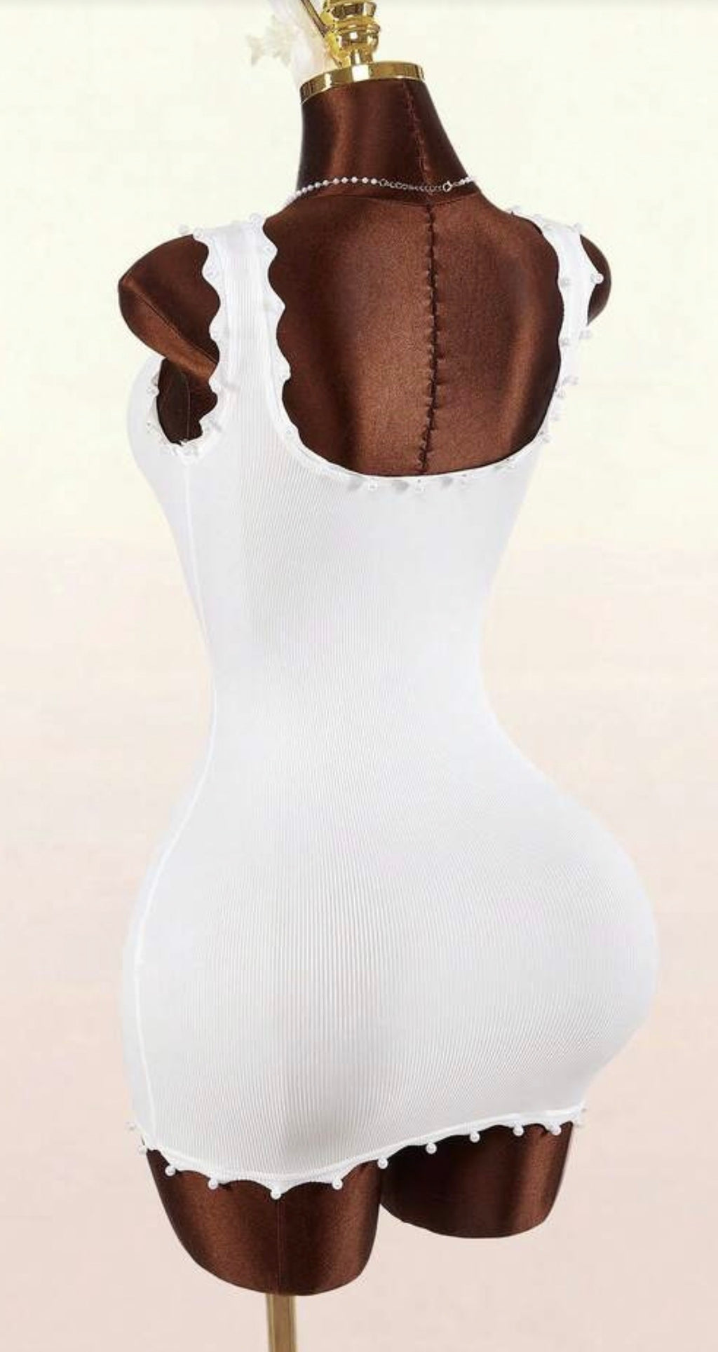White dress with brown accents on a mannequin against a white background